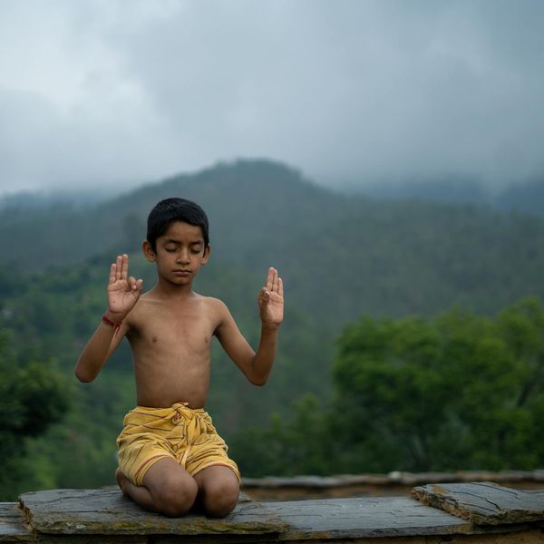 Person meditating outdoors with a serene natural background.